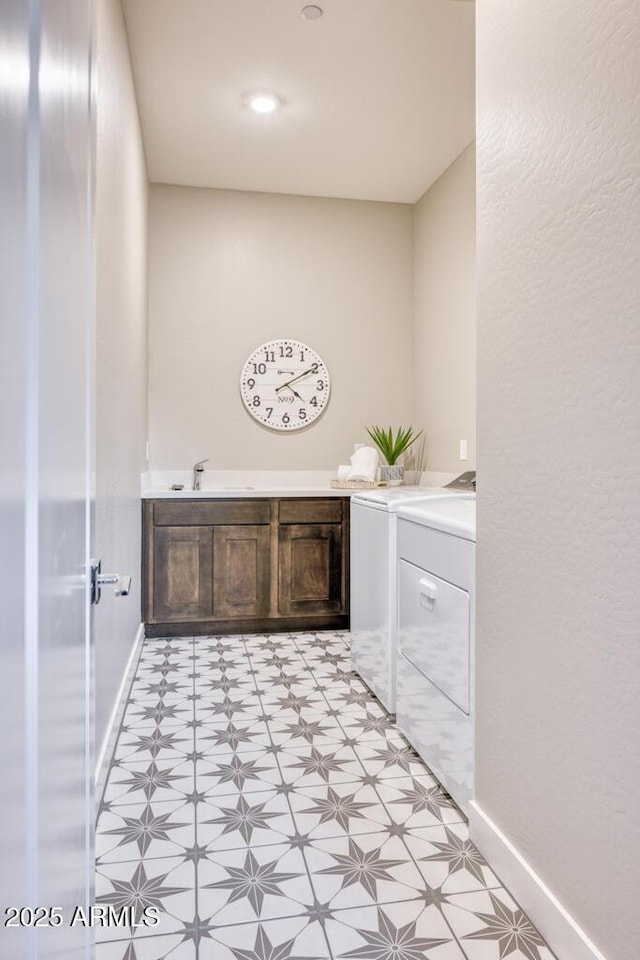 laundry area featuring a sink, baseboards, light floors, laundry area, and washing machine and clothes dryer