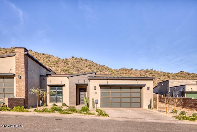 modern home with stucco siding, driveway, an attached garage, and fence