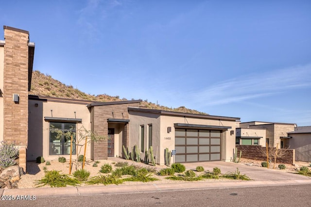 view of front facade featuring fence, a garage, driveway, and stucco siding