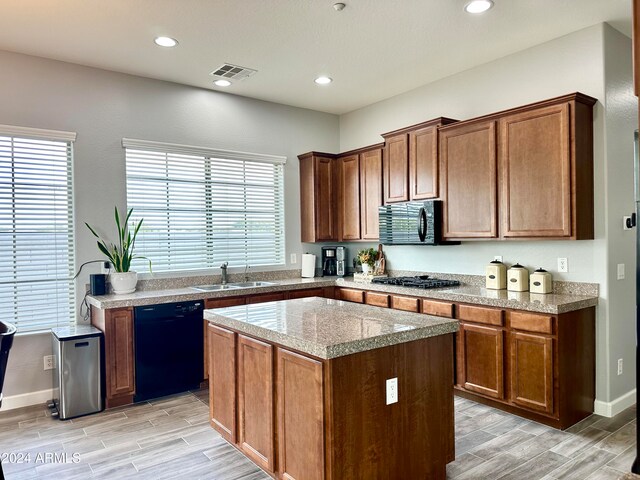 kitchen with sink, a center island, black appliances, and light hardwood / wood-style flooring