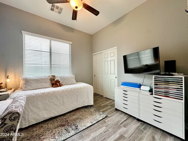 bedroom featuring a closet, light hardwood / wood-style flooring, ceiling fan, and lofted ceiling