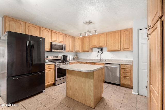 kitchen featuring a textured ceiling, stainless steel appliances, a kitchen island, and light tile patterned flooring