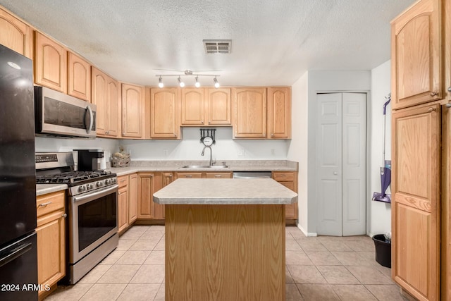 kitchen featuring a kitchen island, sink, light tile patterned floors, and stainless steel appliances