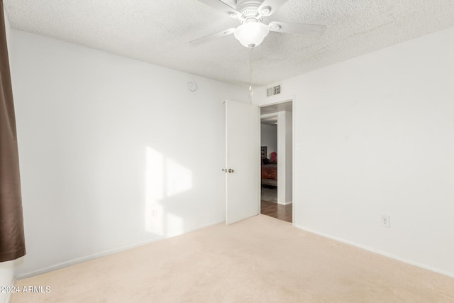 carpeted spare room with ceiling fan and a textured ceiling