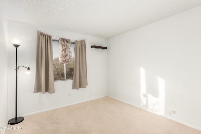 empty room with light carpet and a textured ceiling