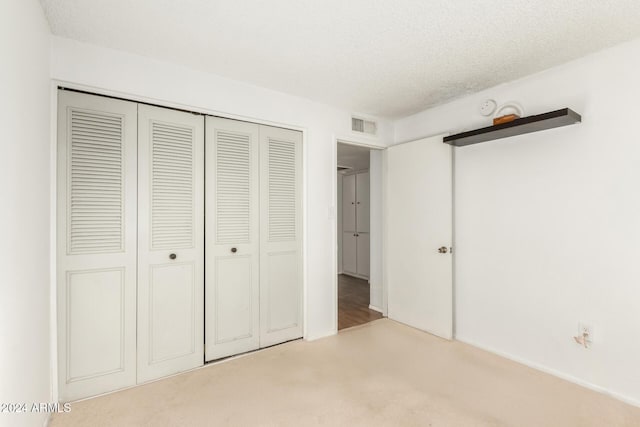 unfurnished bedroom featuring light carpet, a closet, and a textured ceiling