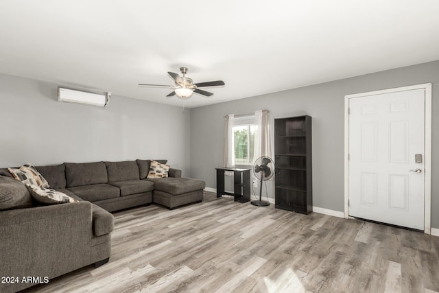 living room with an AC wall unit, ceiling fan, and light hardwood / wood-style floors