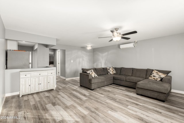 living room with ceiling fan, an AC wall unit, and light hardwood / wood-style flooring