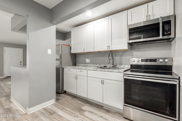 kitchen featuring white cabinets, appliances with stainless steel finishes, light hardwood / wood-style floors, and sink