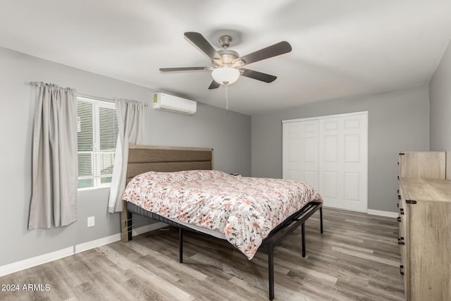 bedroom featuring an AC wall unit, ceiling fan, a closet, and hardwood / wood-style flooring