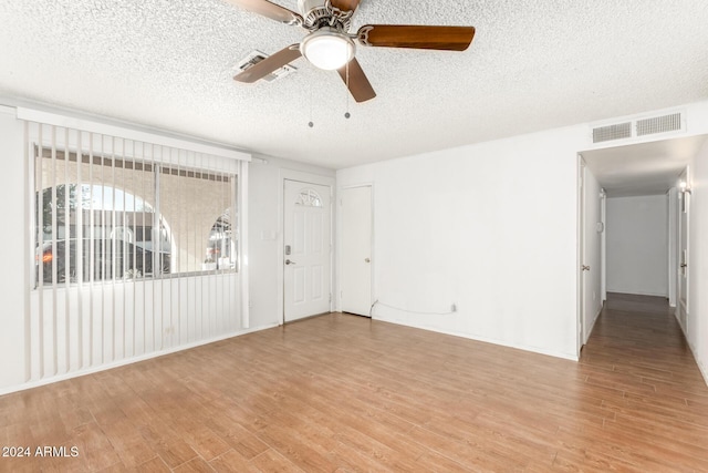 empty room with ceiling fan, light hardwood / wood-style floors, and a textured ceiling