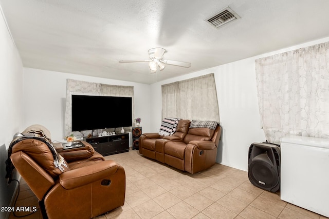 living room with ceiling fan, light tile patterned floors, and a textured ceiling