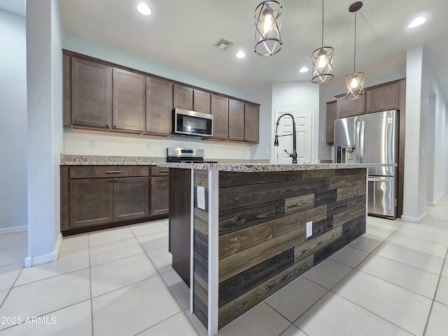19954 W Moonlight Path, Buckeye, AZ 85326 - kitchen featuring appliances with stainless steel finishes, dark brown cabinetry, baseboards, light stone countertops, and hanging light fixtures