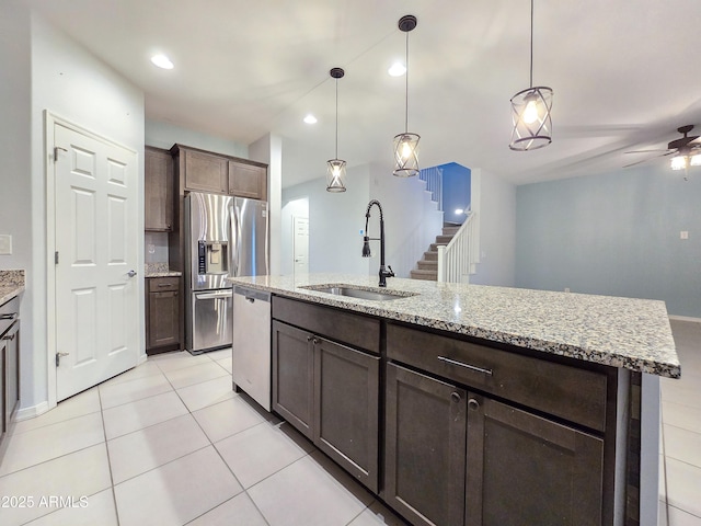 19954 W Moonlight Path, Buckeye, AZ 85326 - kitchen featuring a sink, appliances with stainless steel finishes, light tile patterned flooring, dark brown cabinetry, and light stone countertops