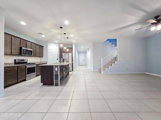 19954 W Moonlight Path, Buckeye, AZ 85326 - kitchen with stainless steel appliances, open floor plan, a sink, dark brown cabinets, and recessed lighting