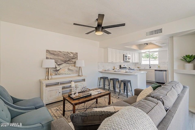 living room with ceiling fan, light hardwood / wood-style floors, and a textured ceiling