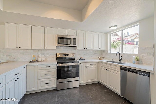 kitchen with sink, white cabinetry, appliances with stainless steel finishes, and dark tile patterned flooring