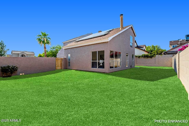 rear view of property featuring a lawn and solar panels