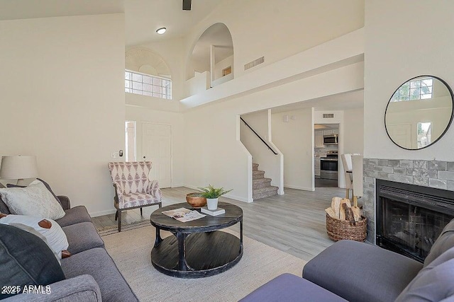 living room featuring high vaulted ceiling, a brick fireplace, a wealth of natural light, and light hardwood / wood-style floors