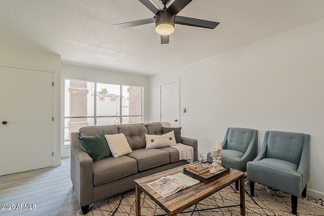 living room with light hardwood / wood-style floors, a textured ceiling, ceiling fan, and a healthy amount of sunlight