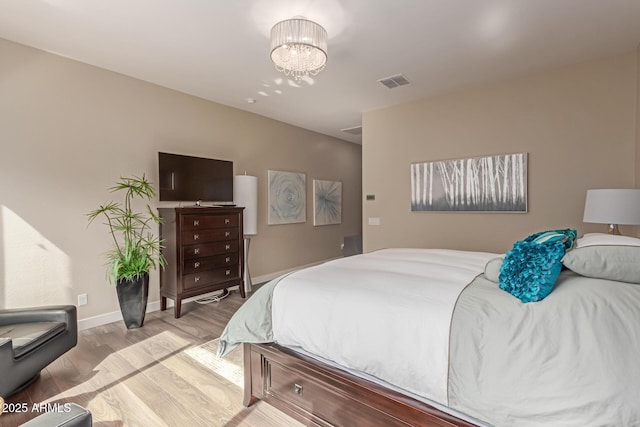 bedroom featuring light wood-type flooring and a notable chandelier