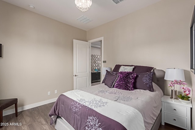 bedroom with dark hardwood / wood-style floors and an inviting chandelier