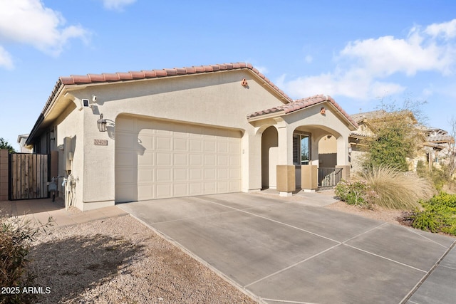 mediterranean / spanish-style home featuring a tiled roof, concrete driveway, an attached garage, and stucco siding