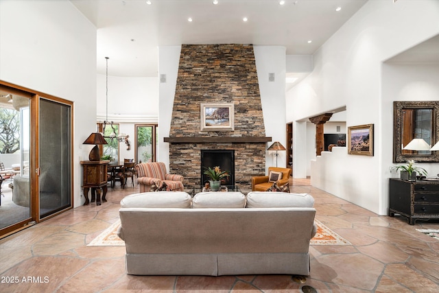 living room with a high ceiling, a stone fireplace, recessed lighting, and stone tile flooring
