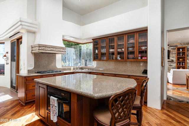 kitchen featuring brown cabinetry, glass insert cabinets, a kitchen breakfast bar, and light wood-type flooring