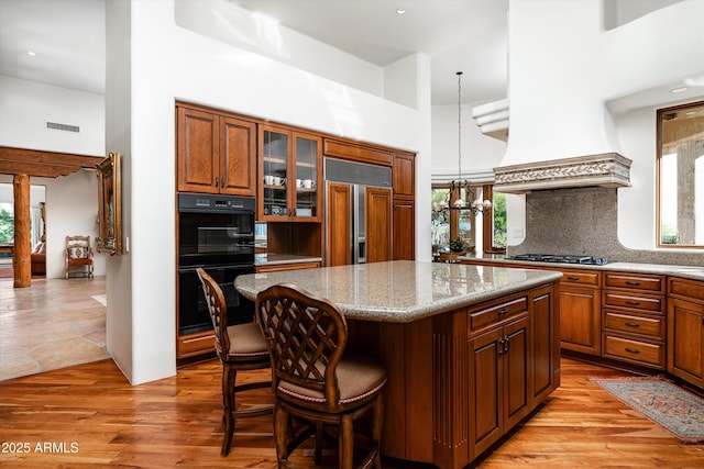 kitchen featuring dobule oven black, paneled built in refrigerator, a high ceiling, and a healthy amount of sunlight