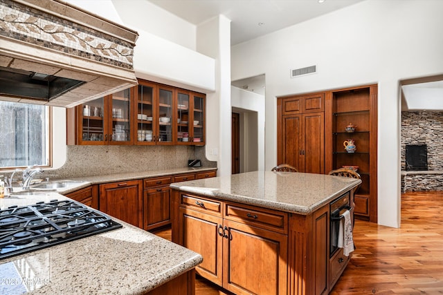 kitchen featuring light wood-style floors, a high ceiling, black appliances, and brown cabinets