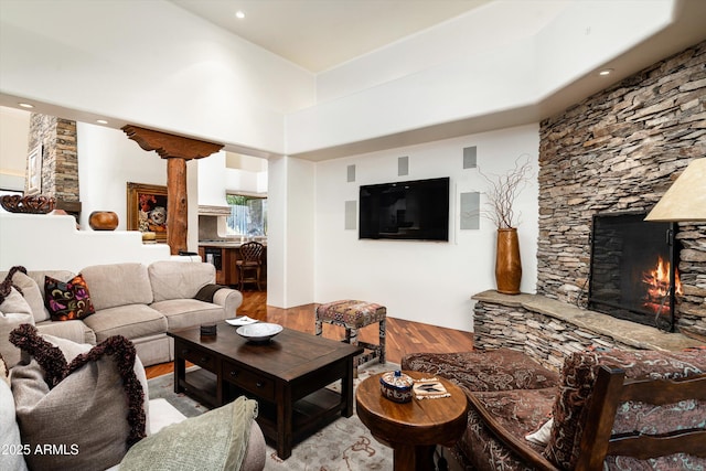 living room featuring recessed lighting, decorative columns, a stone fireplace, and wood finished floors