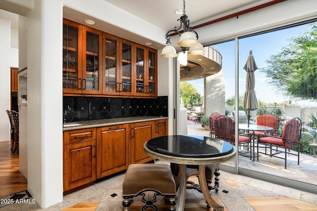 bar with a healthy amount of sunlight, backsplash, and decorative light fixtures