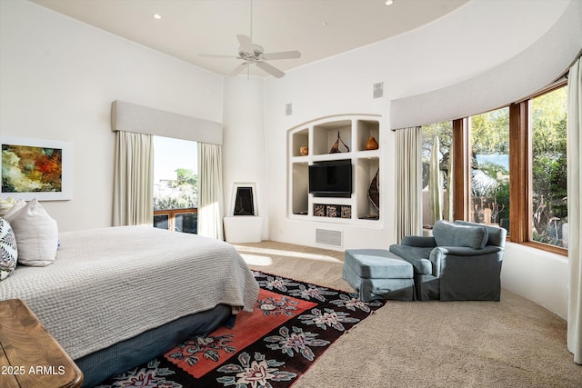 carpeted bedroom featuring multiple windows, a high ceiling, and visible vents