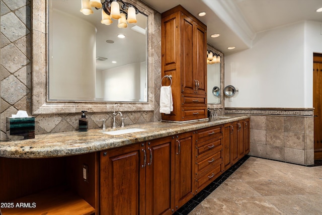bathroom featuring double vanity, stone tile floors, tile walls, recessed lighting, and a sink