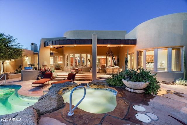 back of house featuring stucco siding, a patio area, and an outdoor pool