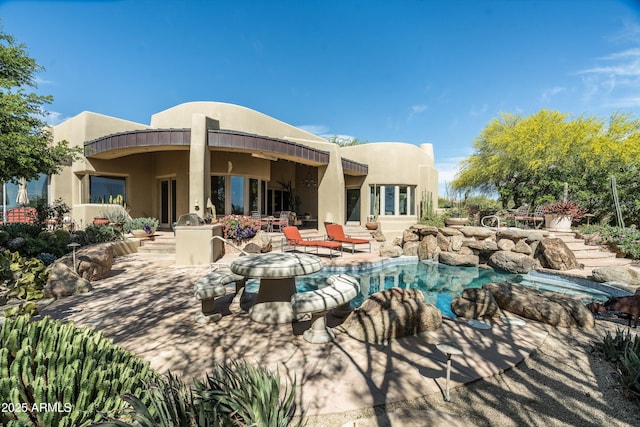 back of house with stucco siding, a patio area, and an outdoor pool