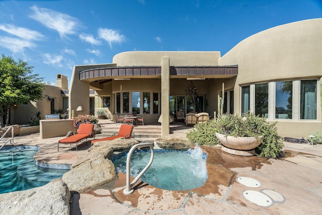 back of property featuring an outdoor pool, a patio area, and stucco siding