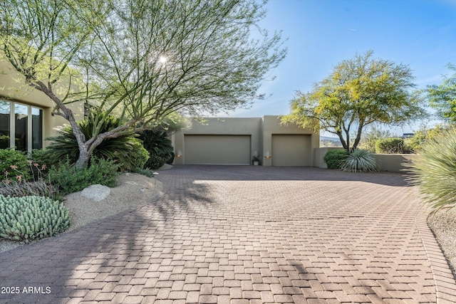view of front facade with an attached garage, stucco siding, and decorative driveway