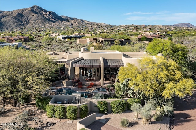 back of property with a mountain view, stucco siding, and a chimney