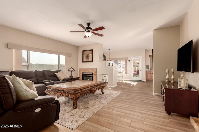 living room featuring a high end fireplace, ceiling fan, and light hardwood / wood-style floors