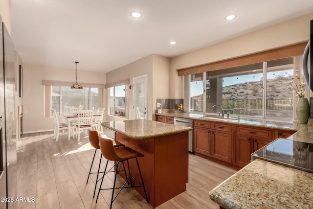 kitchen featuring a kitchen island, stainless steel dishwasher, hanging light fixtures, and sink