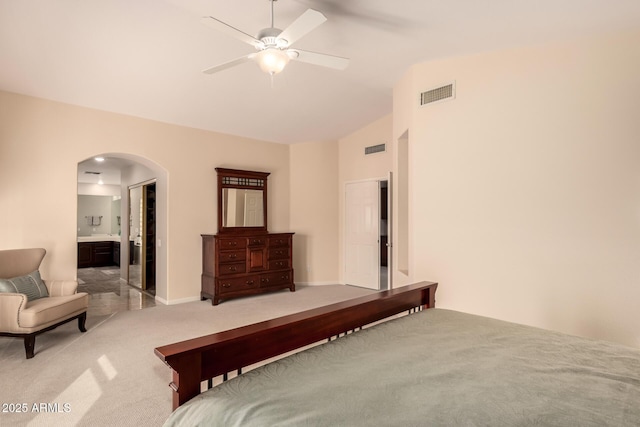 bedroom featuring lofted ceiling, ensuite bath, light colored carpet, and ceiling fan