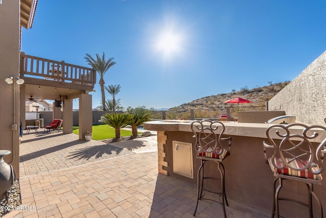 view of patio / terrace with exterior bar, a balcony, and a mountain view