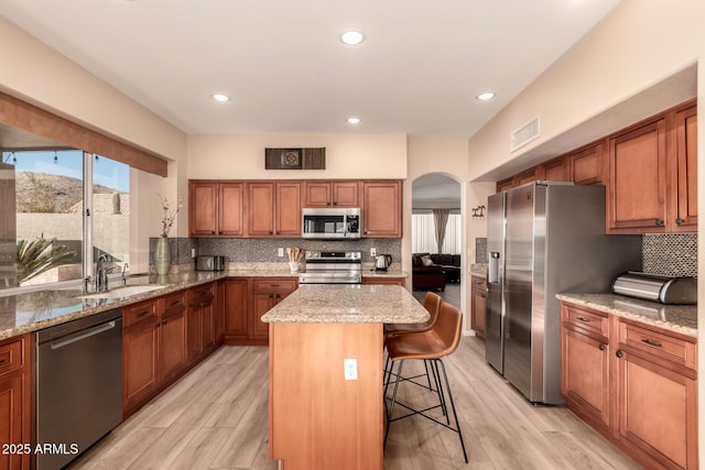 kitchen featuring a center island, stainless steel appliances, a breakfast bar, light wood-type flooring, and sink