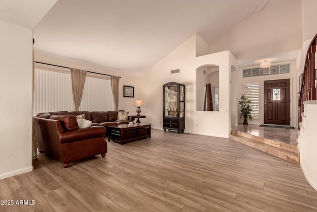 living room featuring high vaulted ceiling and light hardwood / wood-style floors