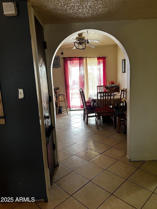 tiled dining area with ceiling fan and a textured ceiling