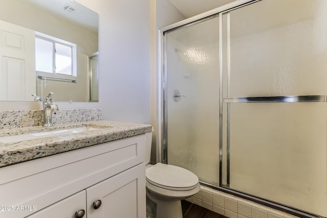 bathroom featuring visible vents, toilet, a shower stall, vanity, and wood finished floors