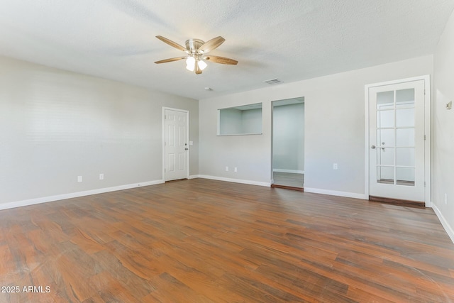 empty room with ceiling fan, a textured ceiling, visible vents, and dark wood-type flooring