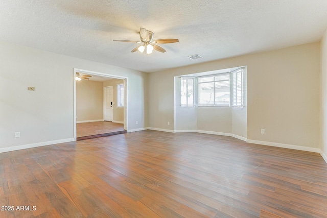 spare room with a ceiling fan, baseboards, visible vents, and dark wood-style flooring